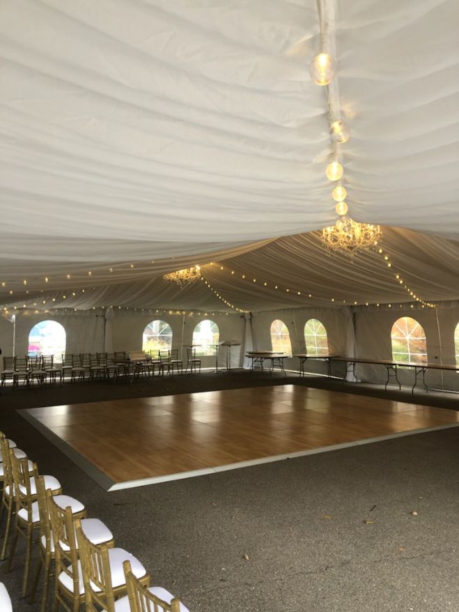 Wedding tent with liner, gold chiavari chairs, birch dance floor, and crystal chandelier